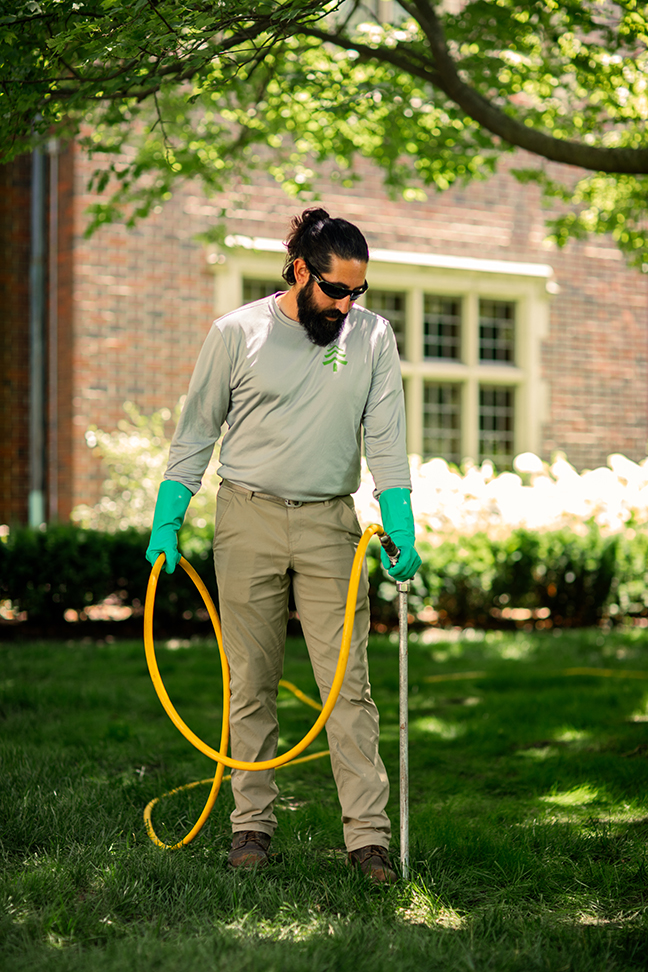 Man injecting herbicides into a tree base.